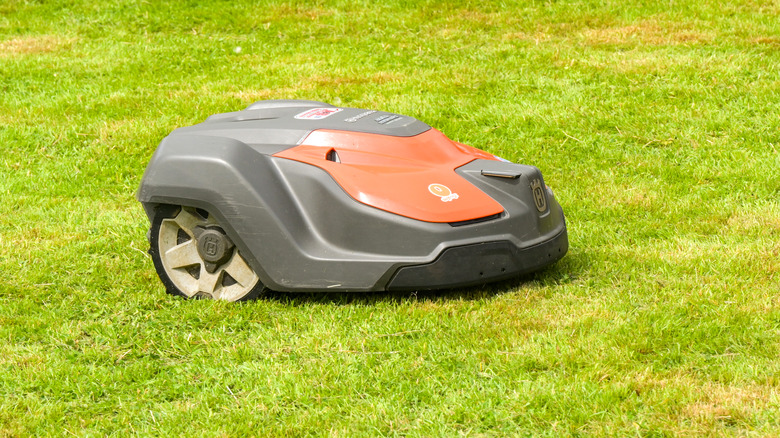 Automatic mowing machine manufactured by Husqvarna running across grass at an outdoor event.