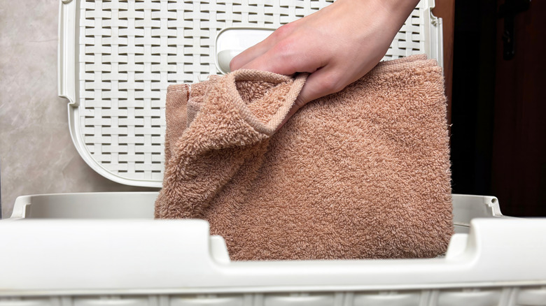 A hand putting a towel into a hamper