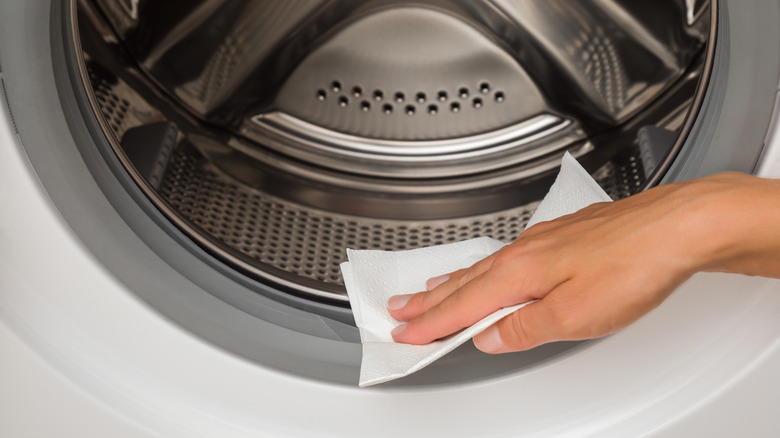 A woman's hand is seen cleaning the gasket of a washing machine