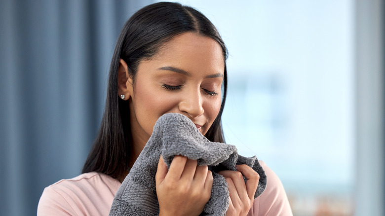 A person smiling and smelling a towel