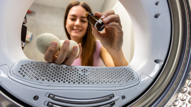 The view from inside a dryer as a woman sprinkled essential oil onto wool balls before adding