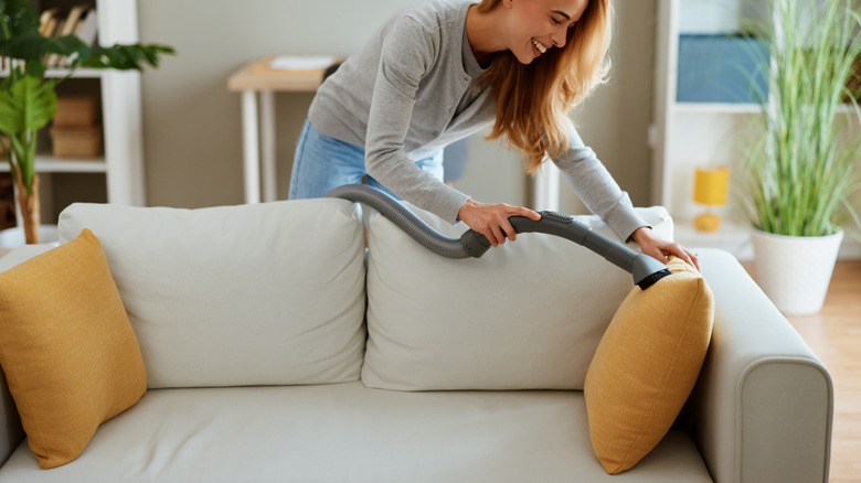 Woman vacuuming the upholstery on a sofa