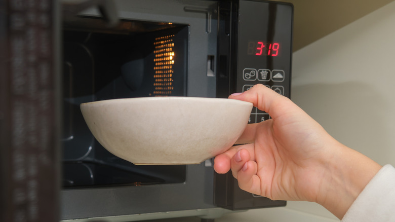 Person putting a bowl into a microwave