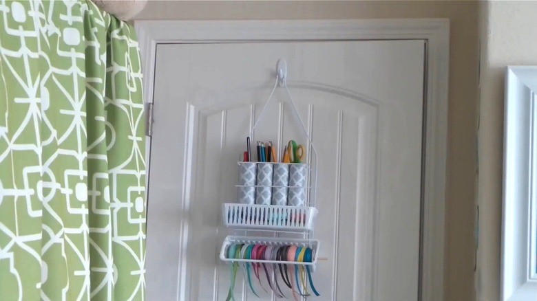 A shower caddy holding crafting supplies hanging on a door
