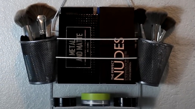 Shower caddy with makeup and makeup brushes on white wall
