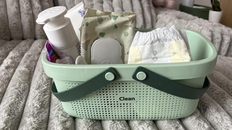 Green shower caddy filled with diapers and baby supplies
