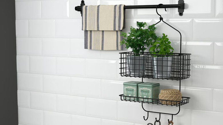 Shower caddy on white wall over kitchen sink with decor and dish towel