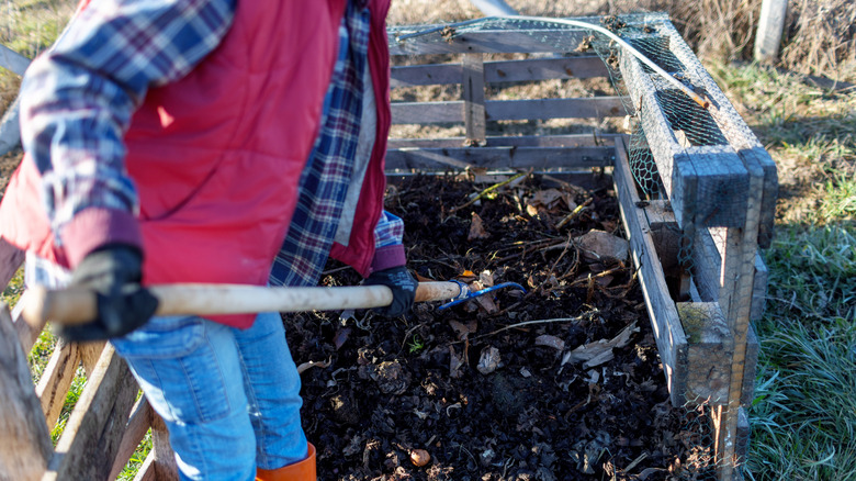person turning compost pile
