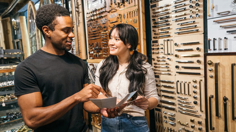 Couple talking in a store in front of a display of cabinet handles and pulls