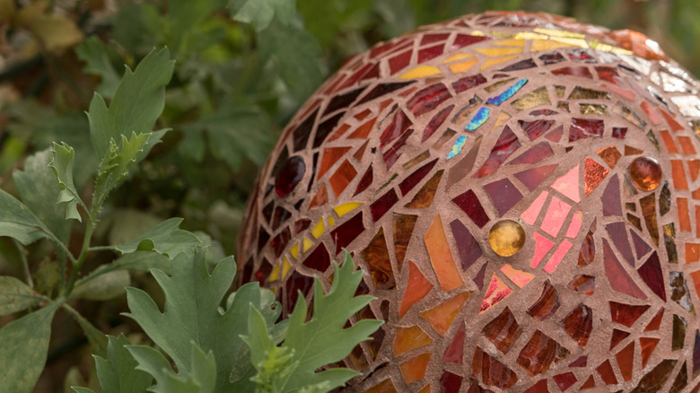 Glazing ball with red and gold tones in garden