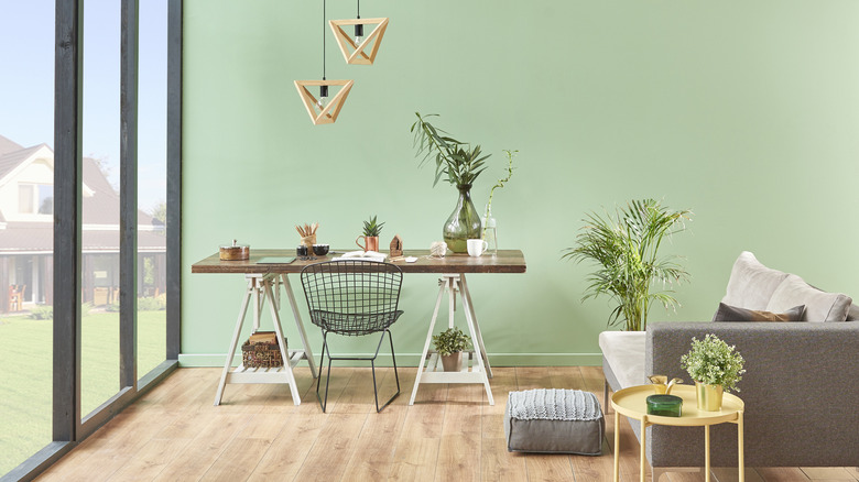 A mint room with a desk full of plants.