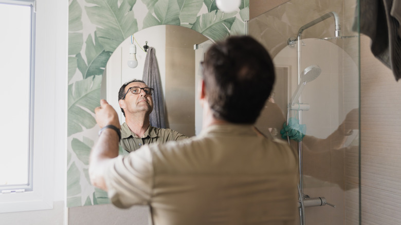 A person hanging a mirror in a bathroom