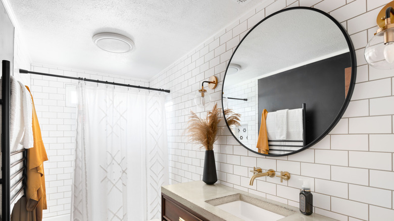 Staged bathroom with large circular mirror on tiled wall