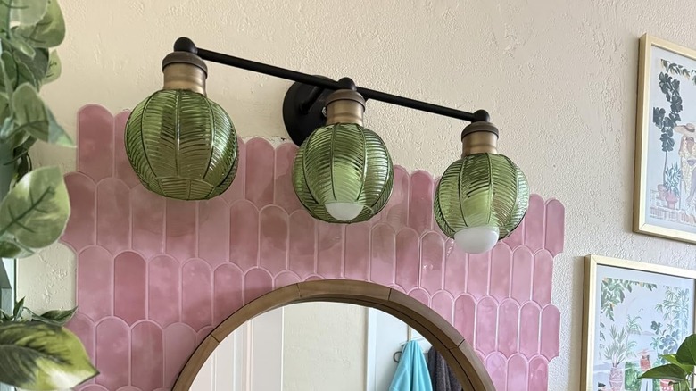 Green glass tulip lamp shades on three-light fixture in bathroom