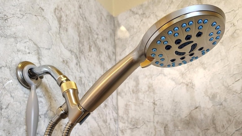 High pressure handheld shower head in bathroom with stone-like tile walls
