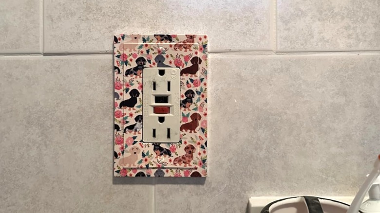 Decorative outlet with dogs and flower pattern in bathroom