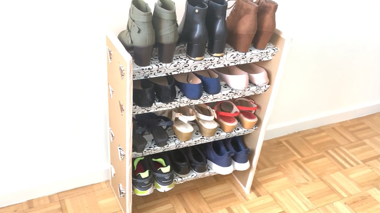 Four-shelf shoe rack made from cardboard with several pairs of shoes on it