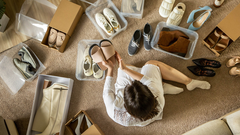 Woman sitting on the floor organizing several pairs of shoes