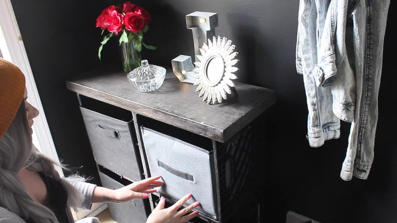 Woman pushing a fabric bin into a spot on a milk crate cube storage shelf