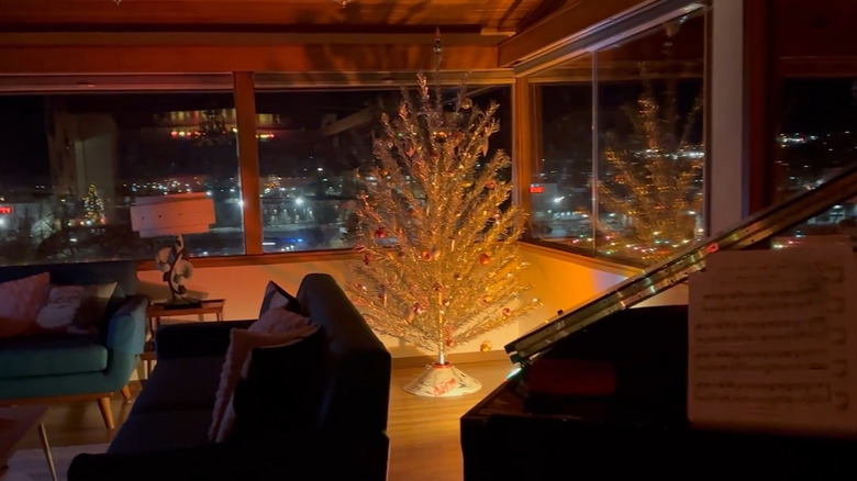 Couple setting up a vintage aluminum Christmas tree with vintage ornaments on it