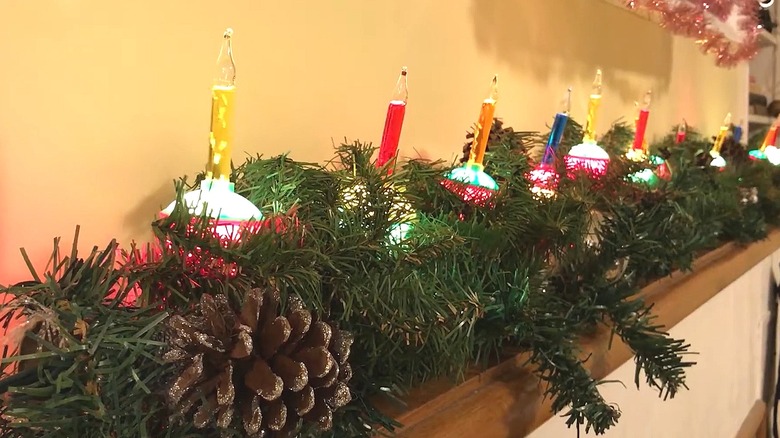 Vintage bubble lights arranged among evergreen boughs on a mantel