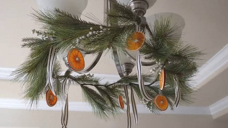 DIY dehydrated orange slice garland hanging from a light fixture with pine boughs