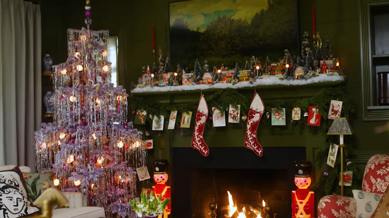 Tinsel-covered tree next to a fireplace