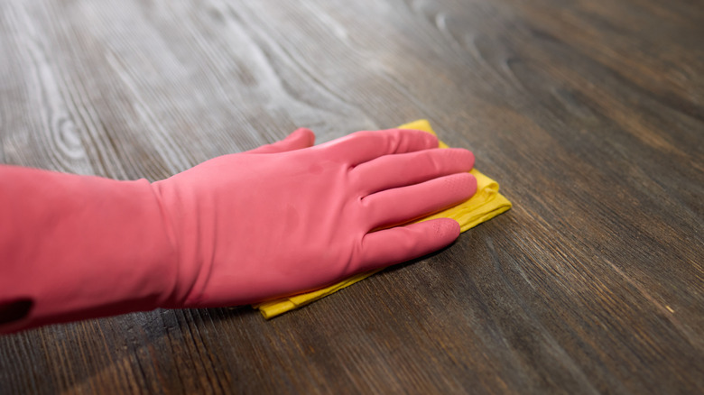 A gloved-hand polishing a wooden floor