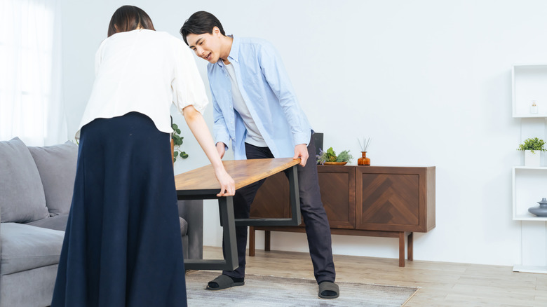 Two people moving a coffee table