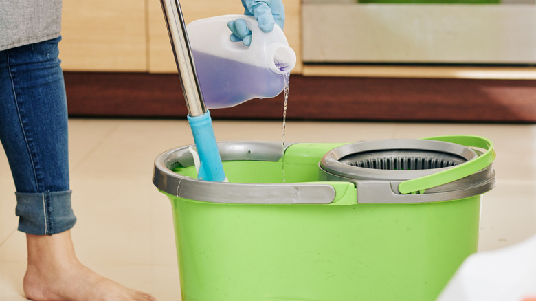 A person pouring cleaner into mop bucket