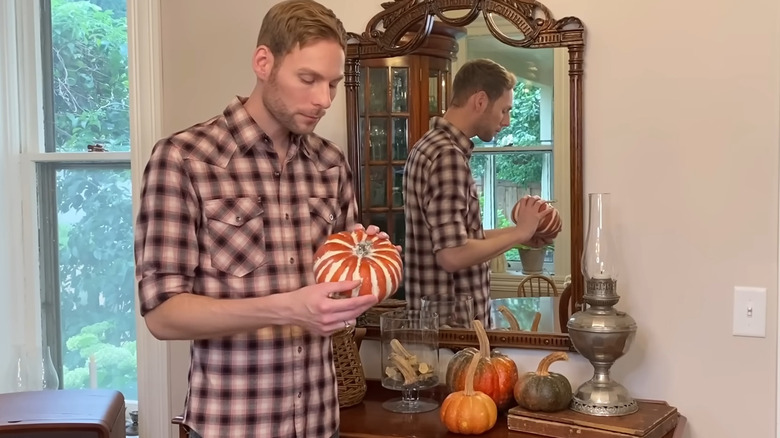 A person replacing the stems on artificial pumpkins