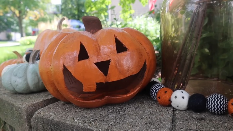 An orange jack-o'-lantern placed outside on a brick surface