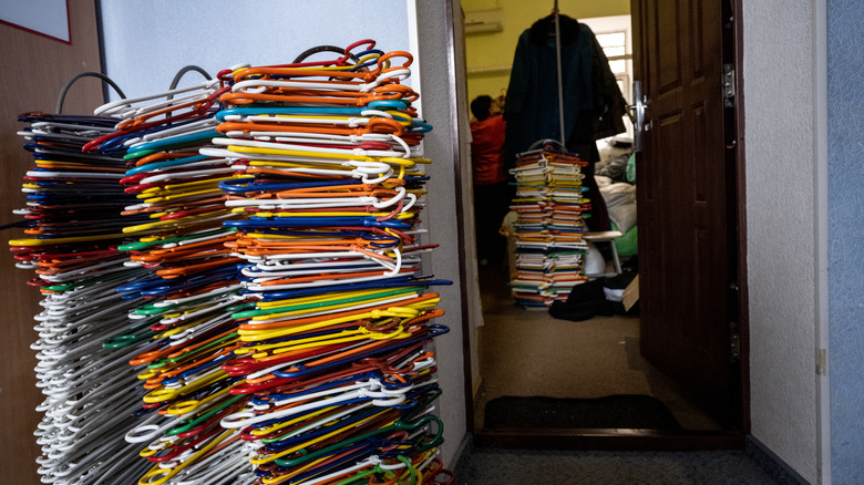 An enormous pile of disused plastic coat hangers in many colors in the corner of a room.