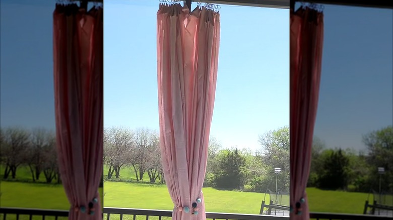 Pink bedsheet hanging from an outdoor patio with Dollar Store clip rings