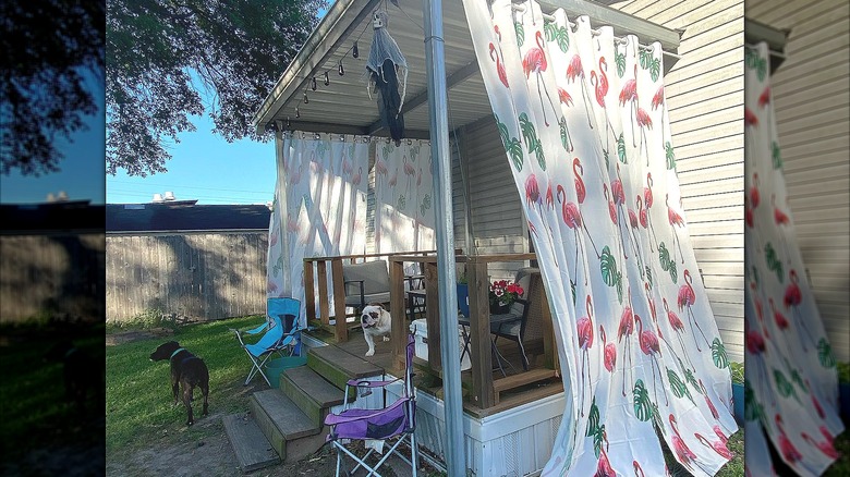 Flamingo print outdoor curtains hanging on a patio with cute dogs