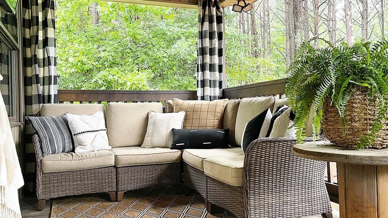 Buffalo check curtains hanging behind an outdoor wicker couch