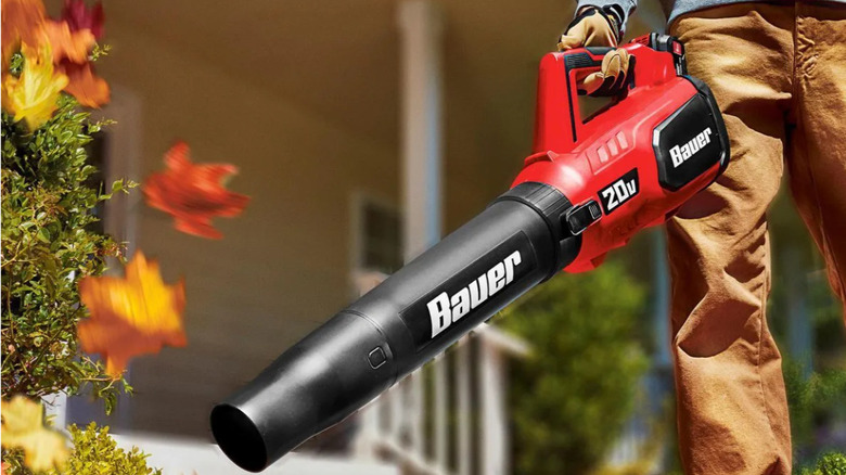 Man using red Bauer jet fan blower to clear sidewalk