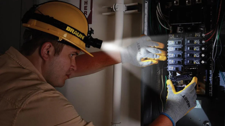 Electrician using Braun headlamp to inspect electrical panel