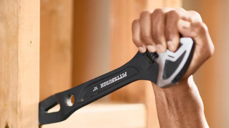 Hand using PITTSBURGH pry bar on wooden boards