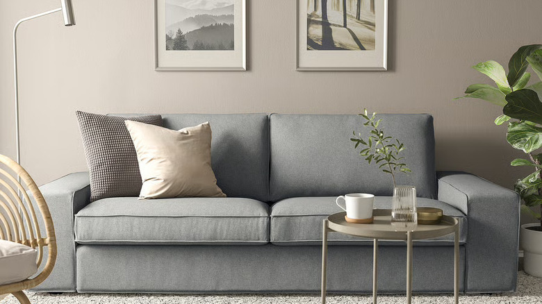 KIVIK sofa with pillows in room against a beige wall with a table in front