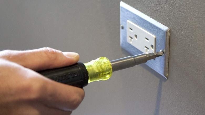 Klein Tools 11-in-1 multi-bit screwdriver and nut driver being used on a power outlet