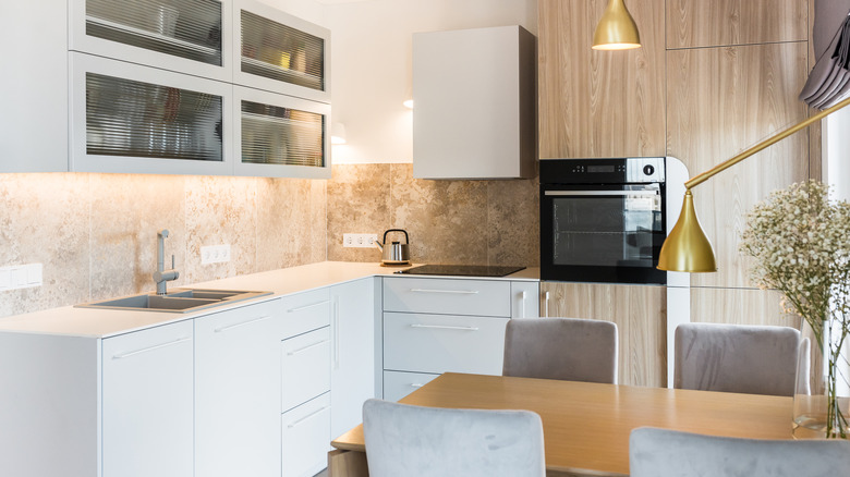 A modern kitchen with white cabinetry and wood accents