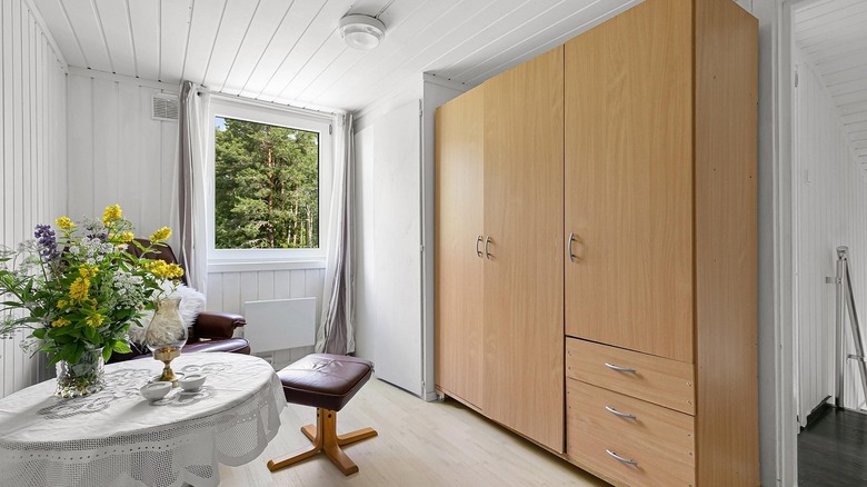 Custom tan cabinet in white room next to table and stool