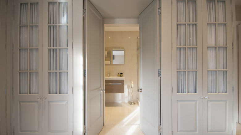 Two French door closets with bathroom door in the middle
