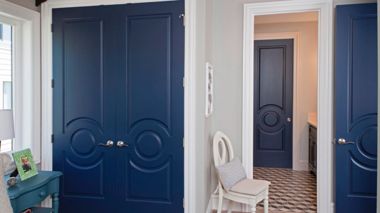 Dark blue closet doors next to a white chair and blue side table