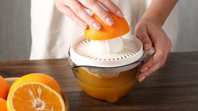 Woman twisting orange on juicer