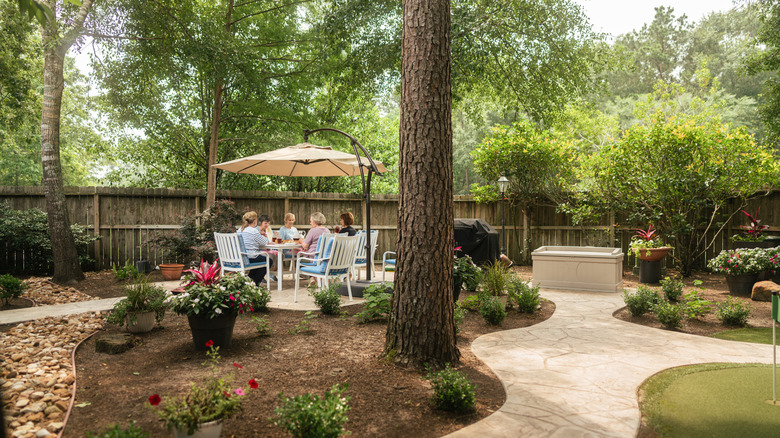 women sitting outside in garden with patio furniture, benches, and other features
