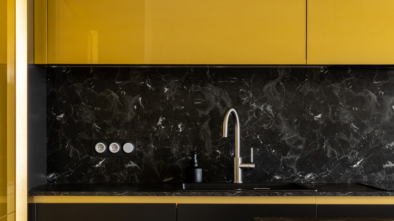 Kitchen with yellow cabinets and black backsplash