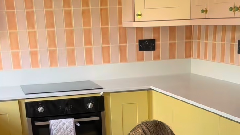Peach and pink tile backsplash in butter yellow kitchen