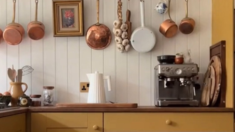 Yellow kitchen cabinets with copper and terracotta pots and pans